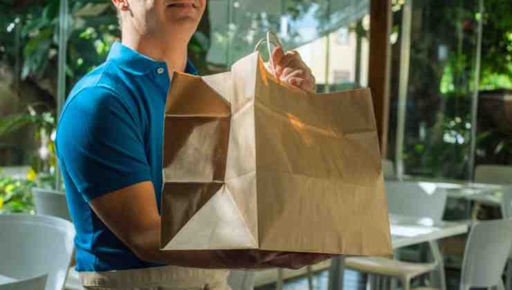 Hombre dando una bolsa de papel a un cliente