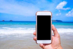celular en mano en la playa